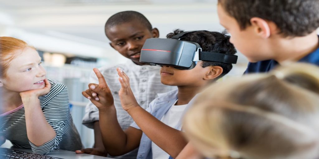 three children looking at one child with vr goggles on