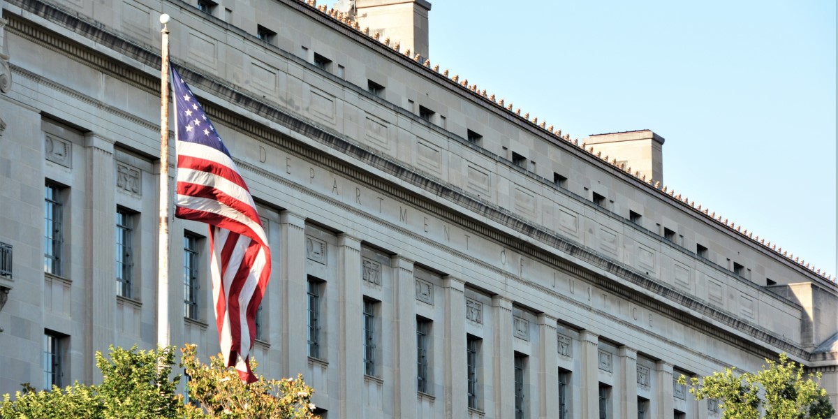 Photo of the Department of Justice Building with US Flag in Front