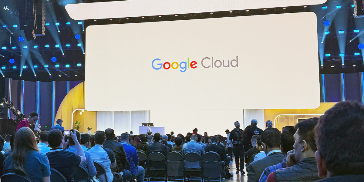 Google Cloud conference room. Huge screen with a crow of people.
