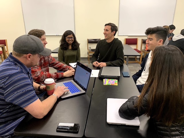 people sitting around a table with laptops