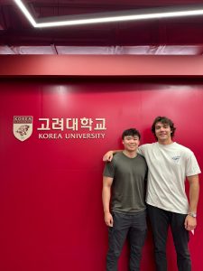 Information science student Nicholas Schiavone and another student standing in front of a red wall.