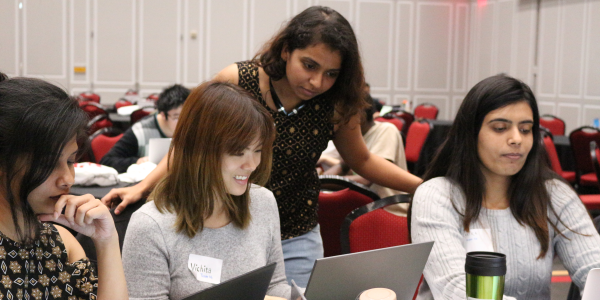 Photo of volunteer helping college students competing at the annual Info Challenge