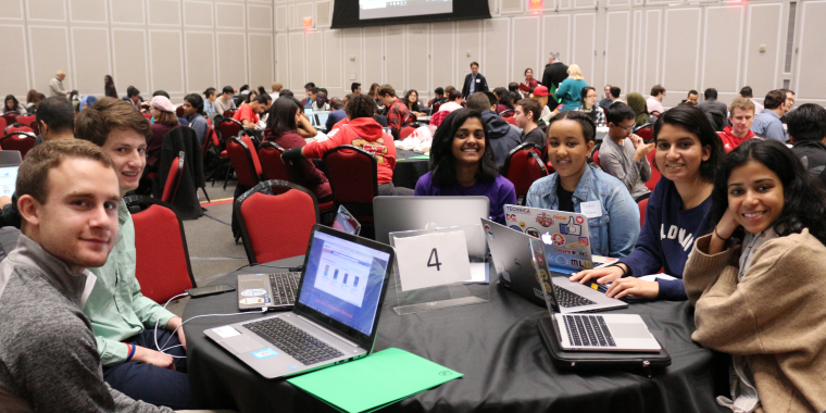 Photo of college students sitting at a table with laptops at the Info Challenge event