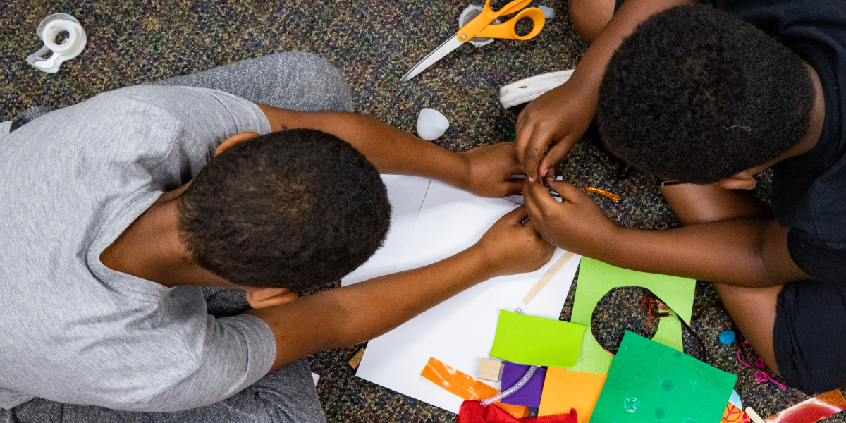 A photo of two children in KidsTeam using found materials to prototype technology