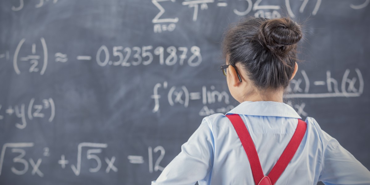 Middle schooler looking at blackboard with equations on it