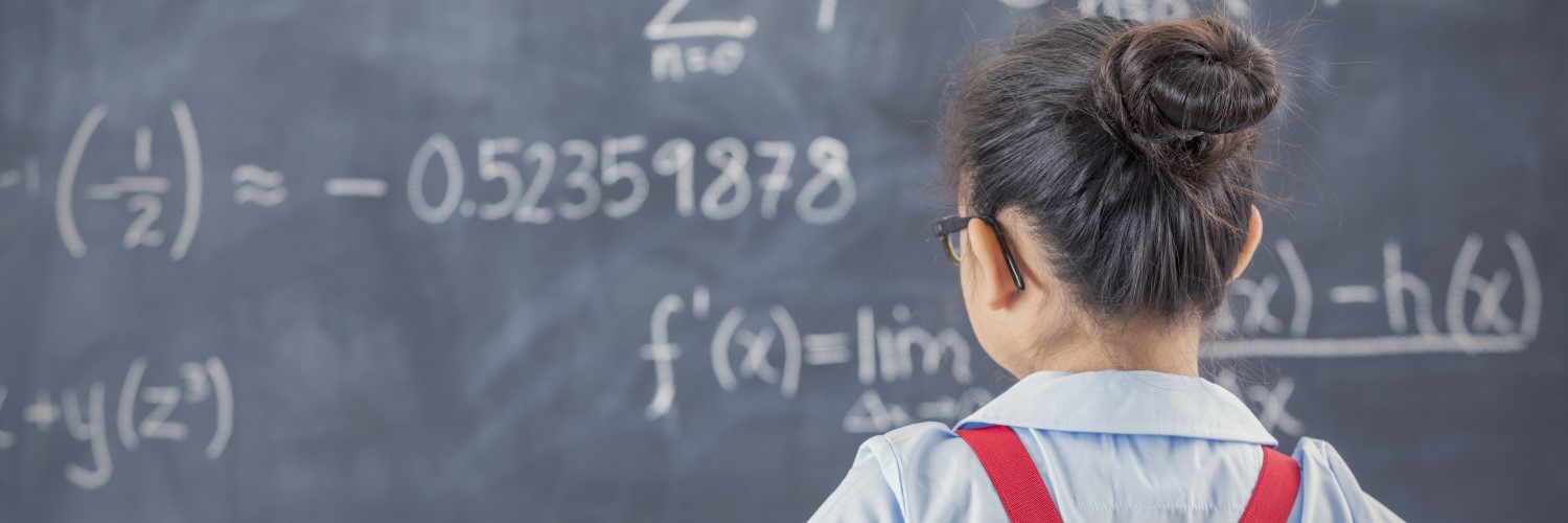 Middle schooler looking at blackboard with equations on it