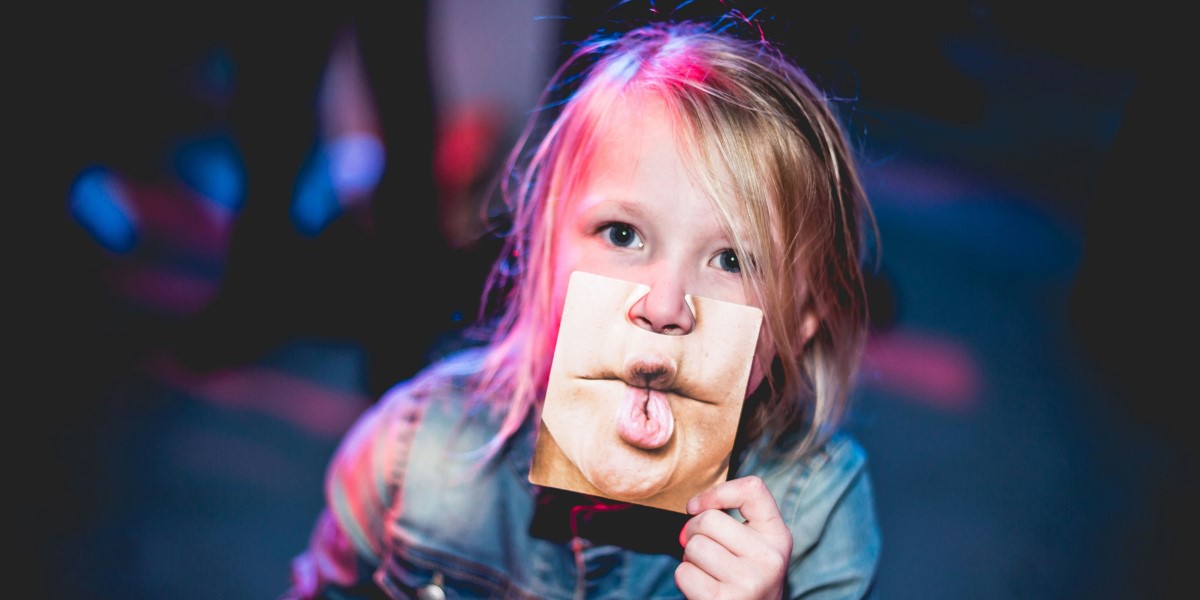 Image of a little girl holding a photo of a nose in front of her own.