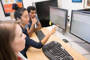 Photo of Three Students Looking at a Computer Together