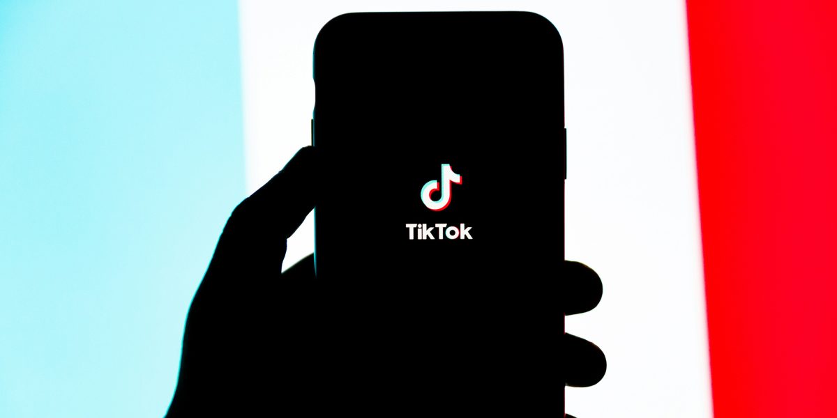 Hand holding a phone with the TikTok app loading.