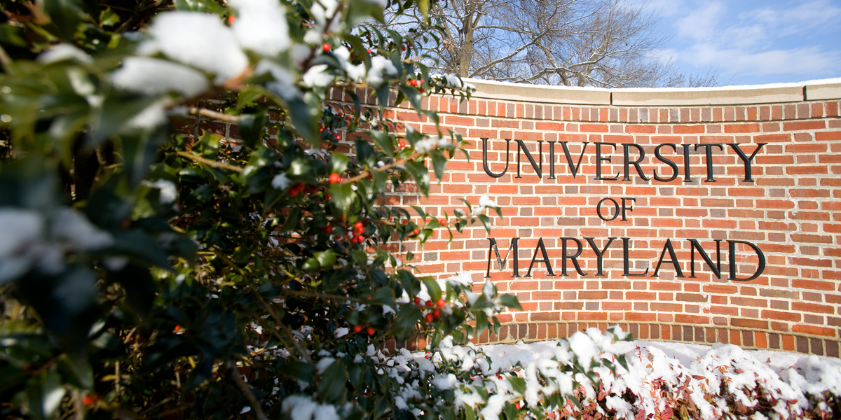 Brick sign saying university of maryland with snow and holly