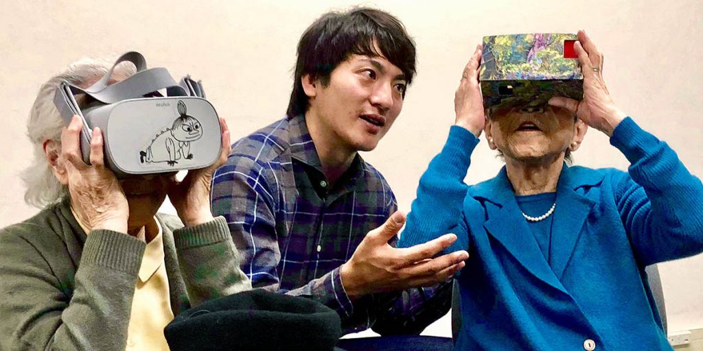 photo of two older women using vr goggles and a younger man between them assisting