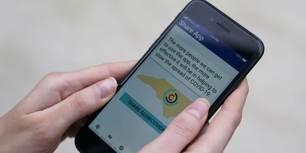 hands holding iPhone with contact tracing app screen