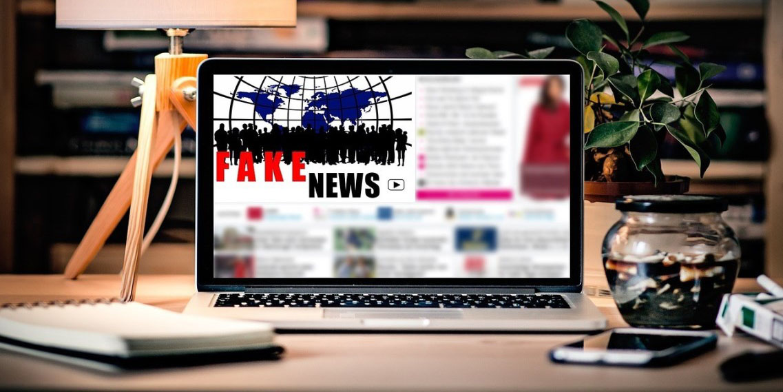 laptop that says "Fake News" on desk