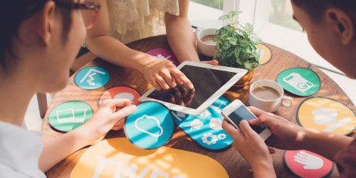 people sitting around a circular table with a tablet and phone