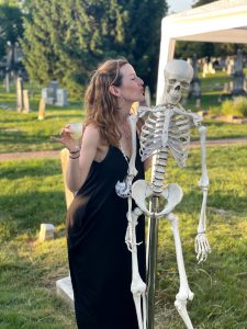 Woman stands with a prop skeleton