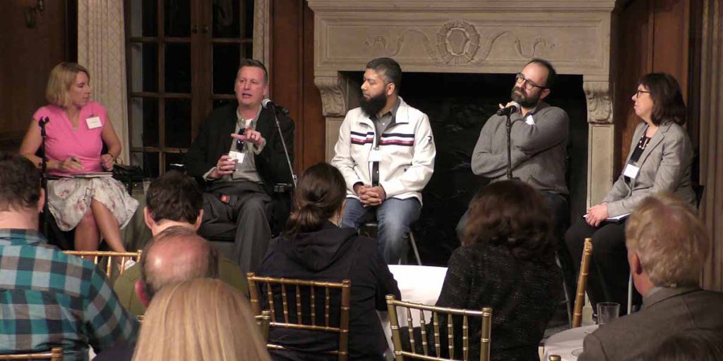 row of people sitting in chairs with a microphone in front of them