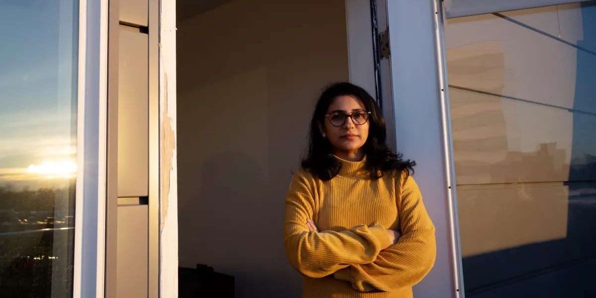 Photo of a woman standing in a doorway with her arms crossed