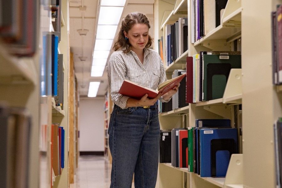 Photo of a librarian in a library looking at a book