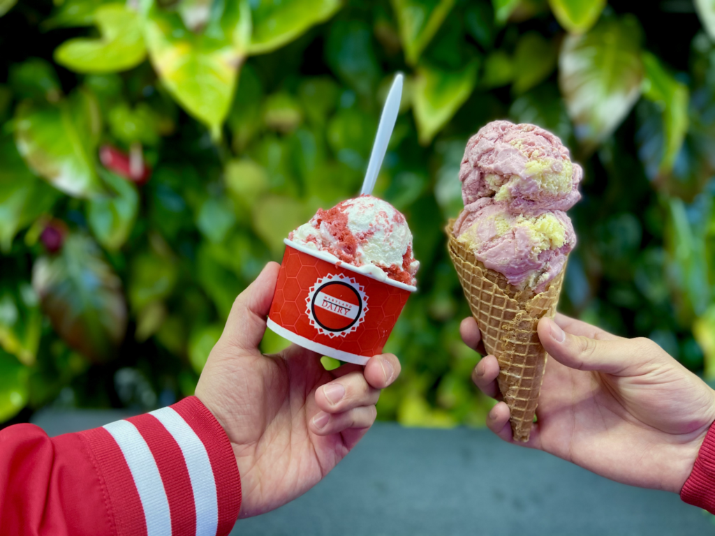 Photo of two hands making a toast with an ice cream cone and a cup of ice cream