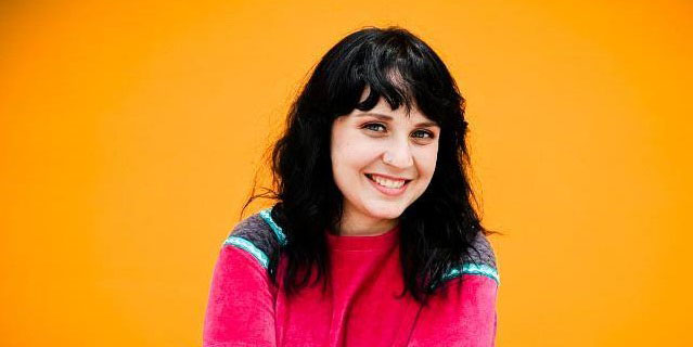 woman smiling in front of an orange background