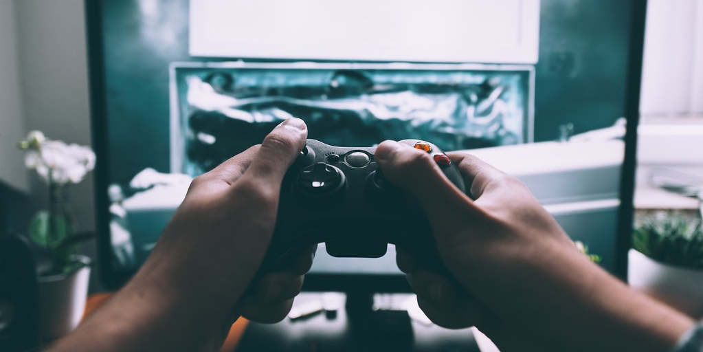 hands on a game controller in front of a tv