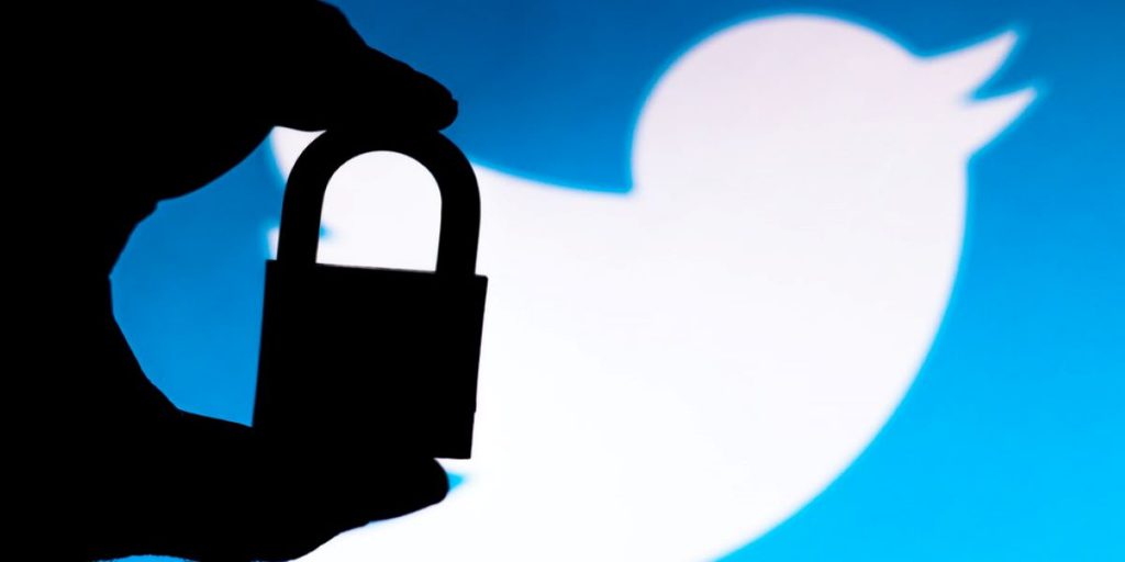 photo of the twitter logo with a shadow of someone's hand holding a lock on top